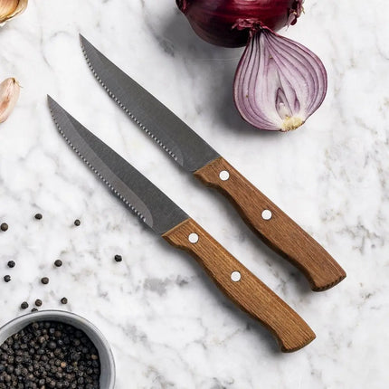 GreenPan steakmessen met houten handvatten, rode ui, knoflook en peper op marmeren oppervlak
