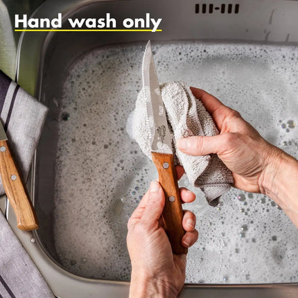 GreenPan steakmes met houten handvat wordt met de hand gewassen in sop met doek, naast tweede mes op gestreepte theedoek