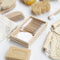 Flatlay van duurzame verzorgingsproducten op witte achtergrond – met houten tandenborstel, kam, borstel, zeep, loofah en scrubhandschoen