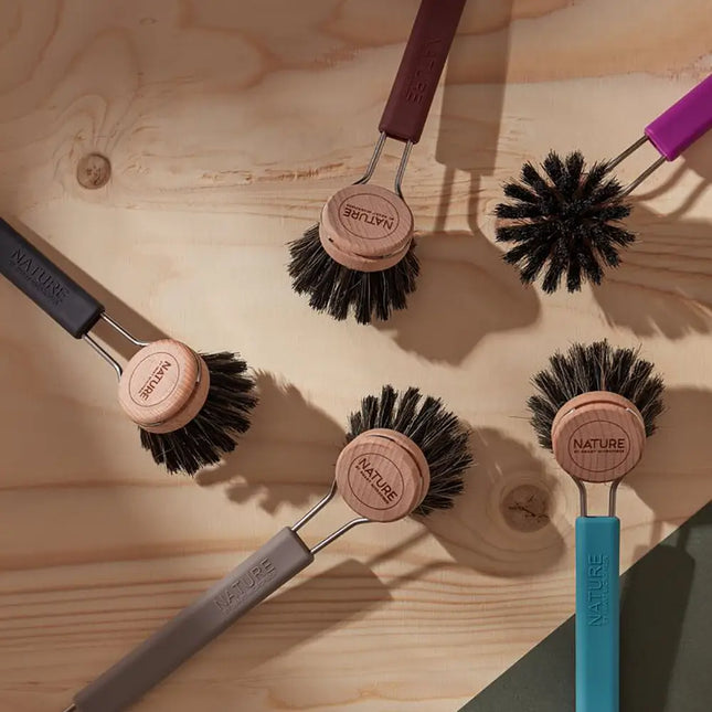 Set afwasborstels met houten borstelkop en zwarte natuurvezelharen in verschillende kleuren op een houten ondergrond.