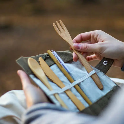 Bambaw bestekset in gebruik tijdens een picknick of outdoor moment, vastgehouden in de hand.