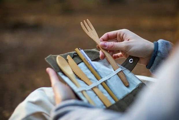 Bambaw bestekset in gebruik tijdens een picknick of outdoor moment, vastgehouden in de hand.