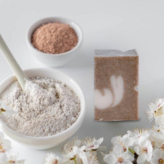Vaste biologische shampoo tegen droog haar met witte klei en natuurlijke poeders, gestyled met bloemen op een witte achtergrond.