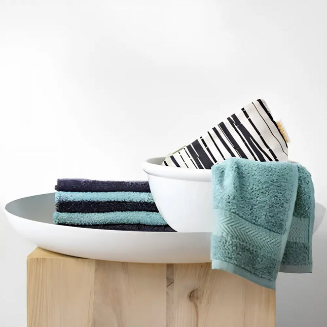 Bo Weevil badstof gezichtsdoekjes in antraciet en mineral green naast witte kommen op een houten krukje