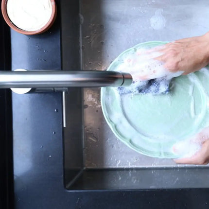 Handen wassen af met schuim van vaste afwaszeep in terracotta kom.