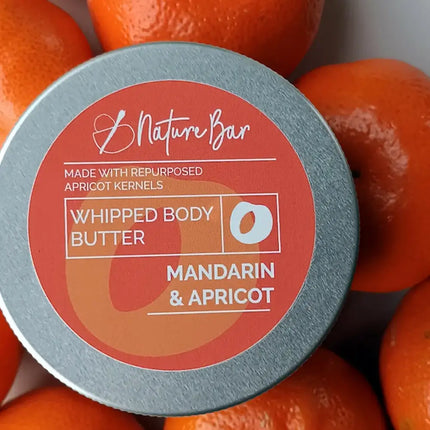 Blikje whipped body butter naast verse mandarijnen