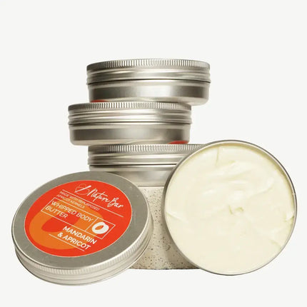Stapel metalen blikjes met whipped body butter mandarijn‑abrikoos