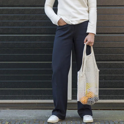 Persoon die buiten een BoWeevil nettas in natural white draagt, gevuld met boodschappen.