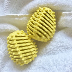 Twee gele Ecoegg wasdrogerballen op een witte handdoek