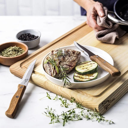 GreenPan steakmessen met houten handvatten bij gegrilde steak, rozemarijn, peper en courgette op houten snijplank