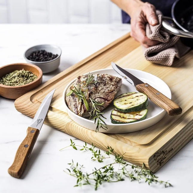 GreenPan steakmessen met houten handvatten bij gegrilde steak, rozemarijn, peper en courgette op houten snijplank
