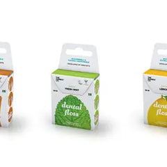 Drie verpakkingen van The Humble Co. flosdraad – kaneel, mint en citroen – elk in gerecycled karton met kleuraccenten die passen bij de smaak