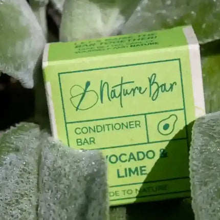 Verpakking van Conditioner Bar Avocado Limoen & Citroengras tussen groene bladeren