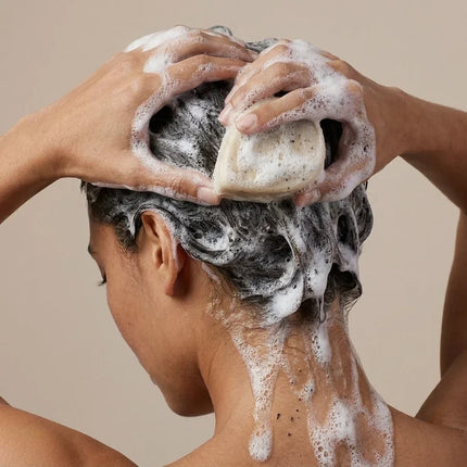 Vrouw wast haar met de Shampoo Bar Voedt & Herstel