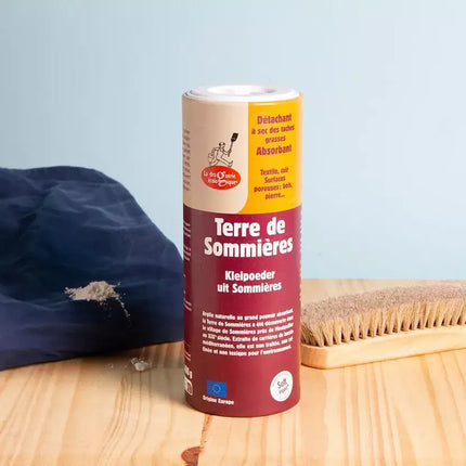  Close‑up van Terre de Sommières kleipoeder met borstel en textiel, gebruikt als natuurlijke droge vlekverwijderaar.