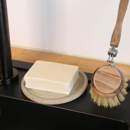 Vaste afwaszeep op een zeepbakje met houten afwasborstel
